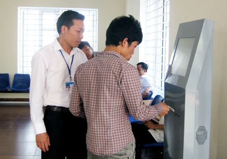 Lãnh đạo Trung tâm HCC TP Uông Bí hướng dẫn người dân tra cứu văn bản trên kiốt điện tử tại Trung tâm HCC TP Uông Bí.
