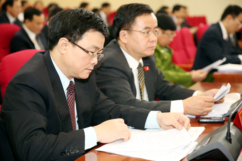 Đại biểu theo dõi báo cáo tóm tắt về tình hình kinh tế- xã hội.