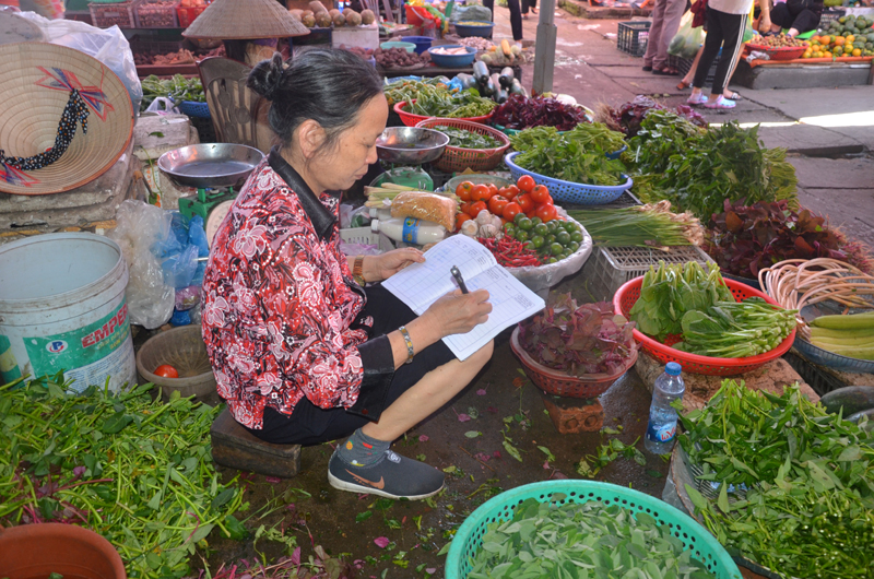Hộ kinh doanh hàng rau ở chợ Trung tâm thành phố ghi chép nguồn gốc hàng hóa vào sổ nhật ký được Ban Quản lý chợ cấp, phát.