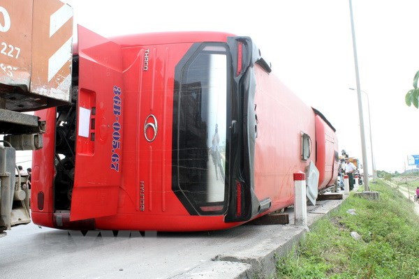 Chiếc xe khách lật nghiêng dưới ruộng được lực lượng chức năng cẩu đưa lên mặt đường. (Ảnh: Tá Chuyên/TTXVN)