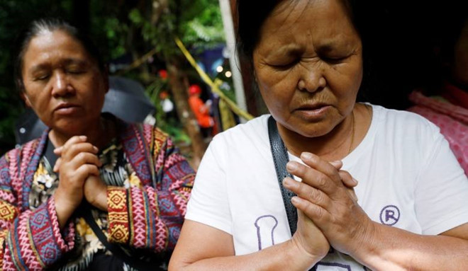 Người nhà cầu nguyện bên ngoài hang động. Ảnh: Reuters.