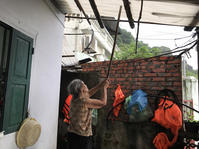 Bà Trương Thị Oanh, khu 4, phường Hồng Gai sống ngay dưới chân núi Bài Thơ lo lắng chỉnh lại tấm mái nhựa khi có mưa lớn.
