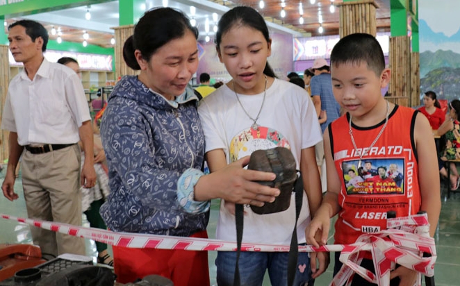 một du khách vui mừng chỉ cho các con chiếc bình tổng thời chị đã từng dùng