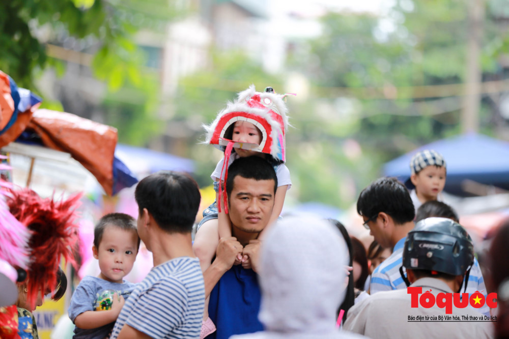 Một em nhỏ đáng yêu đội chiếc đầu lân trên phố Hàng Mã.