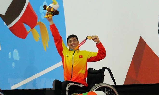 Vận động viên Võ Thanh Tùng tự hào giơ cao tấm Huy chương vàng thứ 3 tại Asian Para Games 2018. (Ảnh: Hải Ngọc/TTXVN)