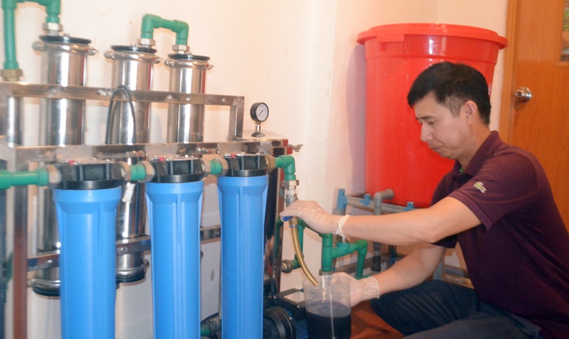 Ông Vũ Văn Minh, Giám đốc HTX Kinh doanh dịch vụ nông, lâm sản ngoài gỗ Ba Chẽ kiểm tra rượu sau khi xử lý qua máy lọc an đê hít
