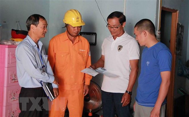 Cán bộ Điện lực hướng dẫn chủ nhà trọ giá bán điện theo quy định mới. (Ảnh: Phạm Cường/TTXVN)