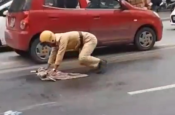 Nam cảnh sát cặm cụi lau vết dầu tràn ra đường. 