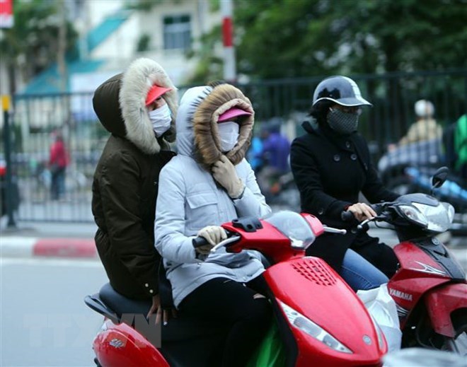 Người dân Hà Nội trang bị áo ấm chống rét, trên đường Giải Phóng. (Ảnh: Danh Lam/TTXVN)