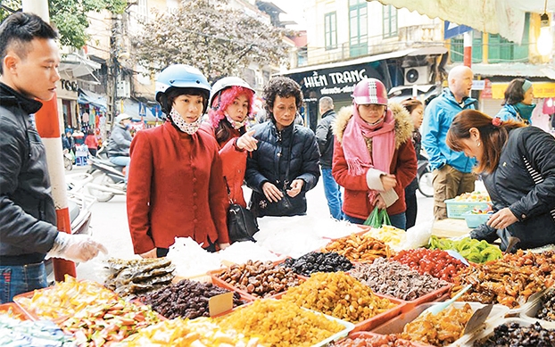 Khách mua bánh kẹo, mứt... tại phố Hàng Buồm (quận Hoàn Kiếm). Ảnh: BẢO NGỌC