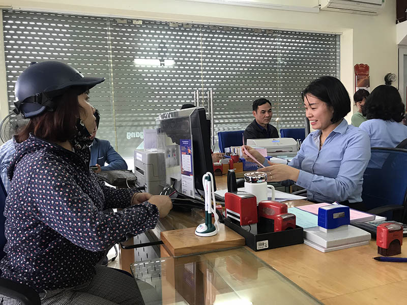 Nhân viên ngân hàng BIDV chi nhánh Quảng Ninh, phòng giao dịch Hồng Hà, TP Hạ Long hướng dẫn người dân làm thủ tục thanh toán tiền điện, nước qua tài khoản tại ngân hàng.