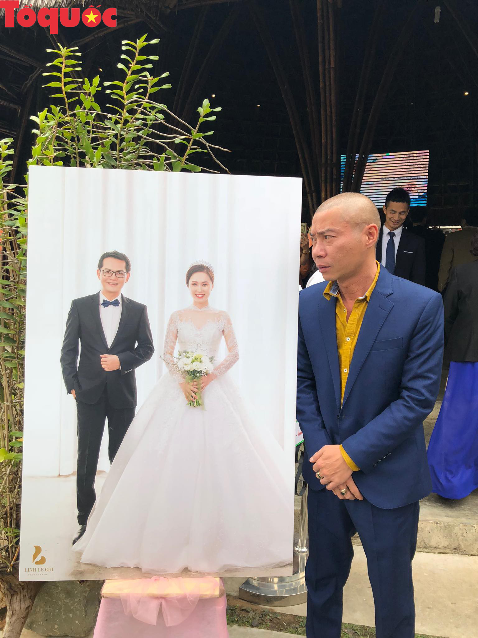 Nghệ sĩ Công Lý chụp ảnh hóm hỉnh bên ảnh cưới của Trung Hiếu và vợ kém 19 tuổi