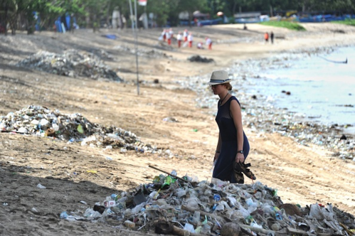 Khách du lịch đi giữa những đống rác được thu gom trên bãi biển Kuta gần Denpasar, Bali. Ảnh: AFP.