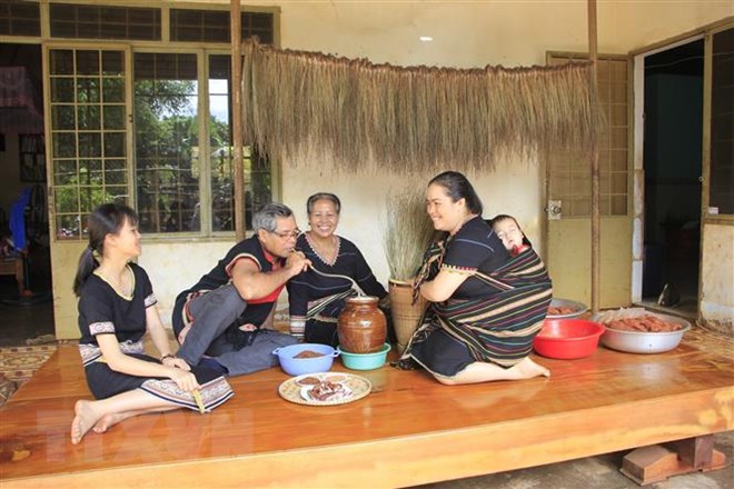 Gia đình quây quần bên nhau thưởng thức các món ăn truyền thống và uống rượu cần. (Ảnh: Hồng Điệp/TTXVN)