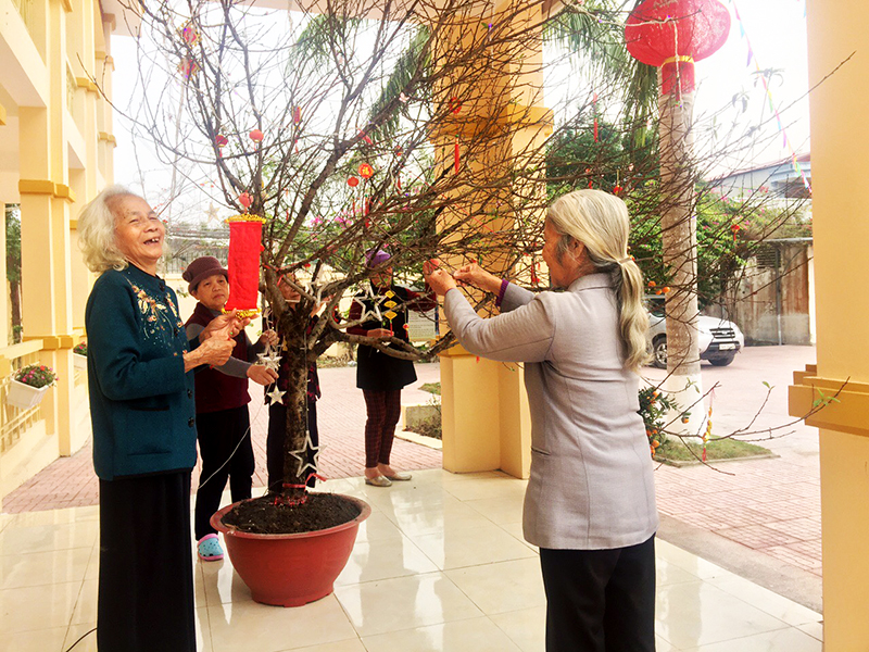 Cụ Nguyễn Thị Bích Thảo (bên trái) cùng các cụ trang trí cành đào đón Tết. 