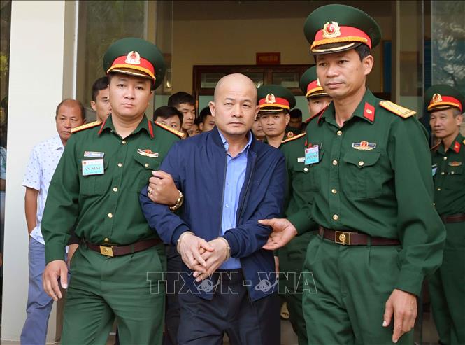 Lực lượng chức năng dẫn giải bị cáo Đinh Ngọc Hệ. Ảnh: TTXVN
