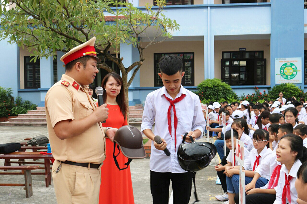 Lực lượng công an thực hiện tuyên truyền, hướng dẫn đội mũ bảo hiểm đúng quy cách cho học sinh 