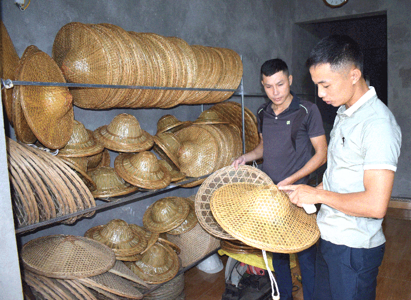 Anh Lý A Tài (bên phải) giới thiệu sản phẩm nón Đại Hiệp với khách hàng - Ảnh: Công Thành