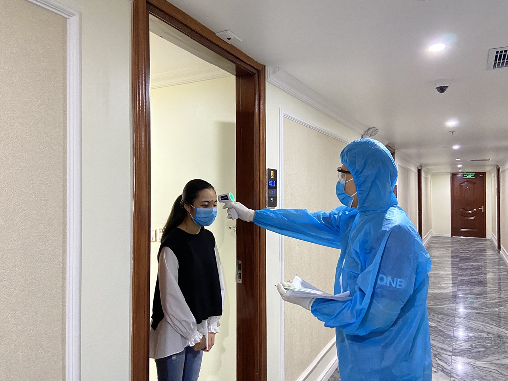 Cán bộ y tế của TP Hạ Long kiểm tra thân nhiệt cho khách cách ly y tế tại khách sạn Thái Sơn.