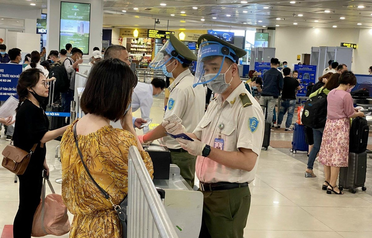 Lực lượng An ninh hàng không Nội Bài được trang bị đầy đủ găng tay, khẩu trang, tấm chắn giọt bắn trong khi tiếp xúc với hành khách. (Ảnh: CTV/Vietnam+)