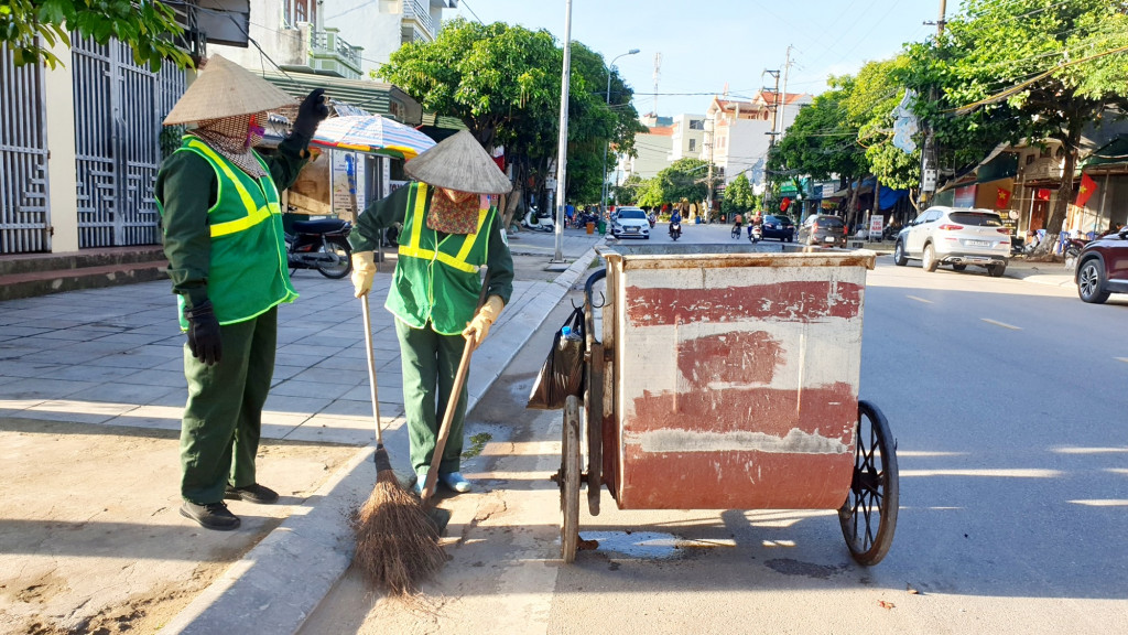 Bà Vũ Thị An (bên trái) cùng đồng nghiệp dọn rác trên một đoạn đường thuộc phường Ka Long, TP Móng Cái.