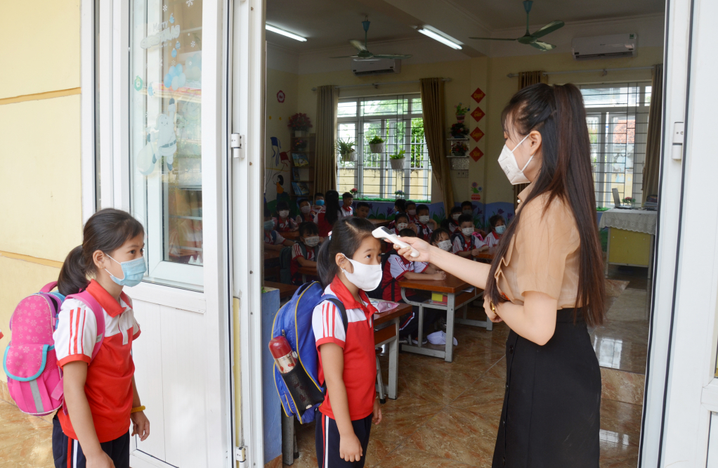 Học sinh đo thân nhiệt khi đến trường. Ảnh chụp tại Trường TH Cẩm Bình, TP Cẩm Phả.